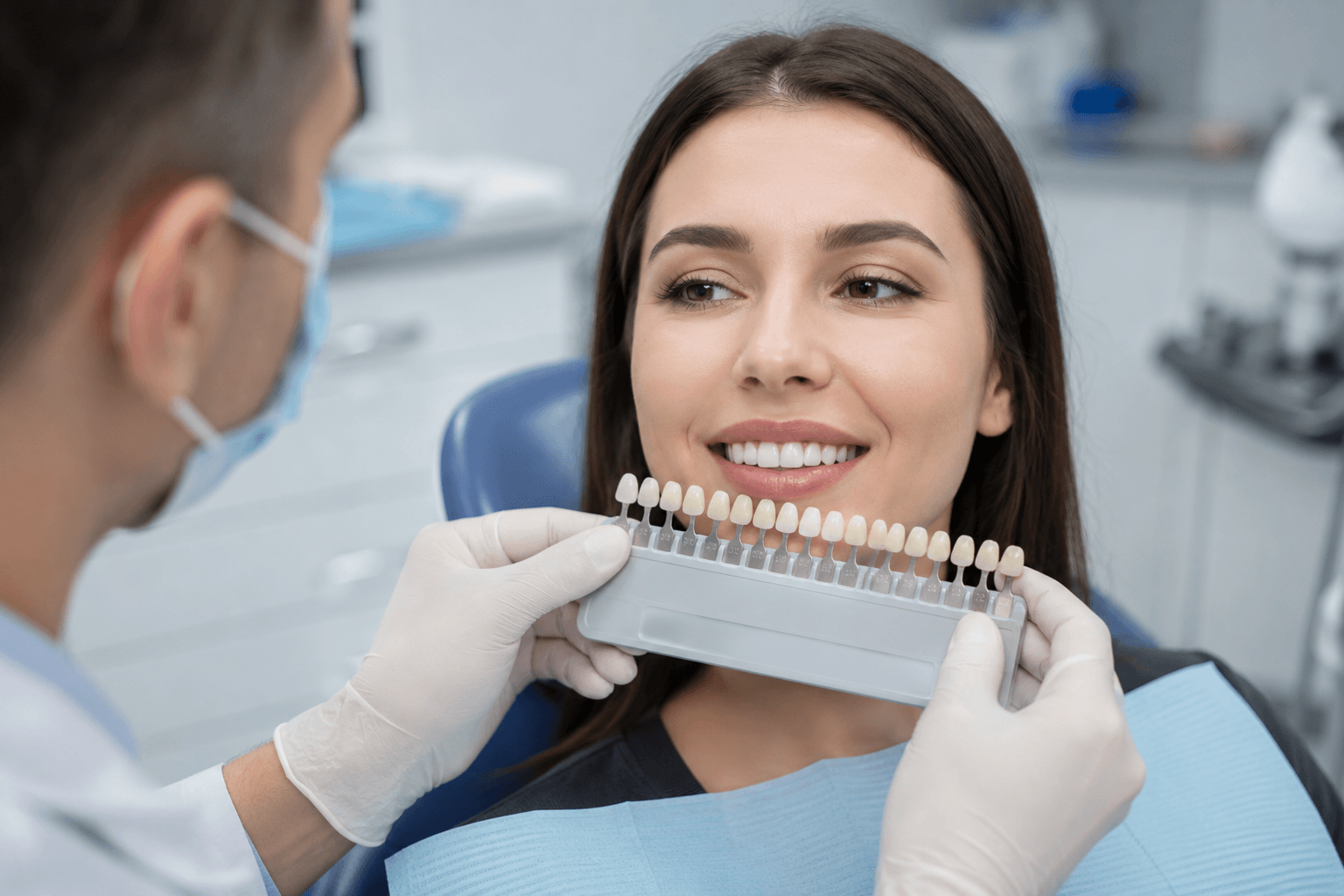 Dentist holding a VITA shade guide next to patient teeth